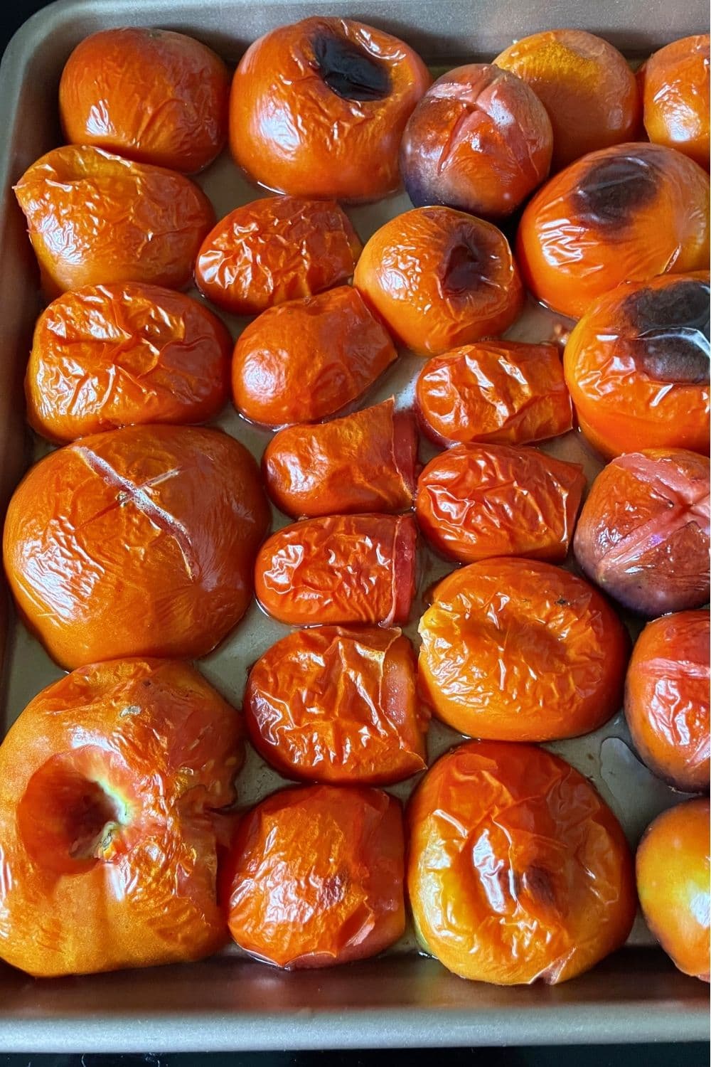 Roma tomatoes beginning to caramelize on a sheet pan