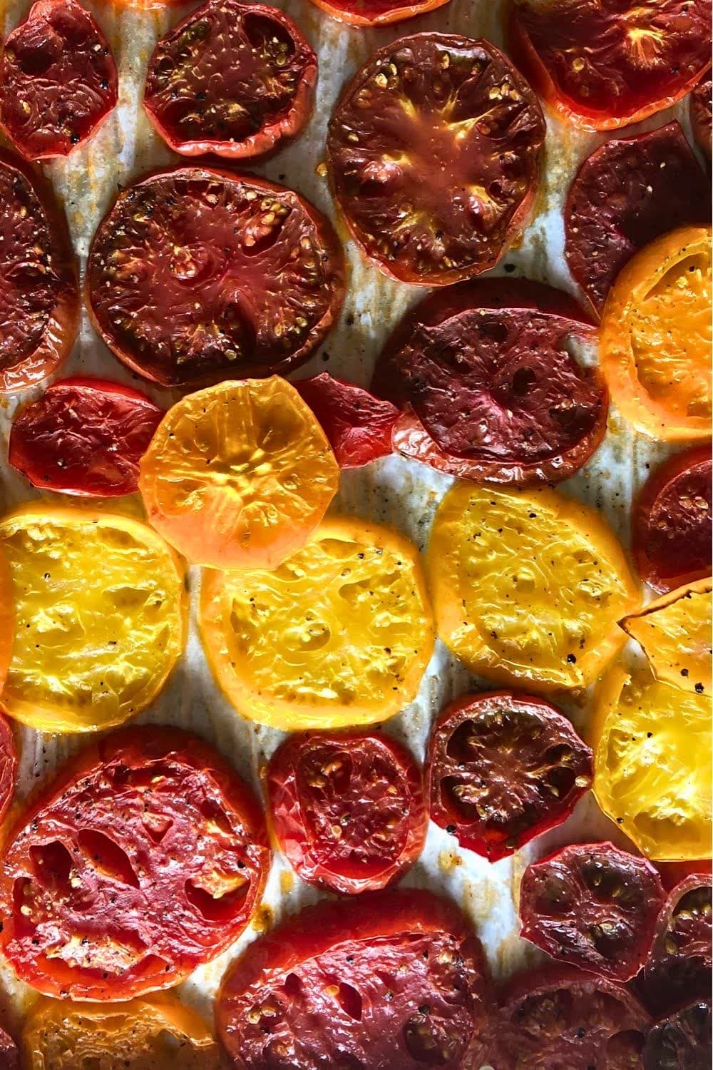 Roasted heirloom tomato slices with caramelized edges on a sheet pan