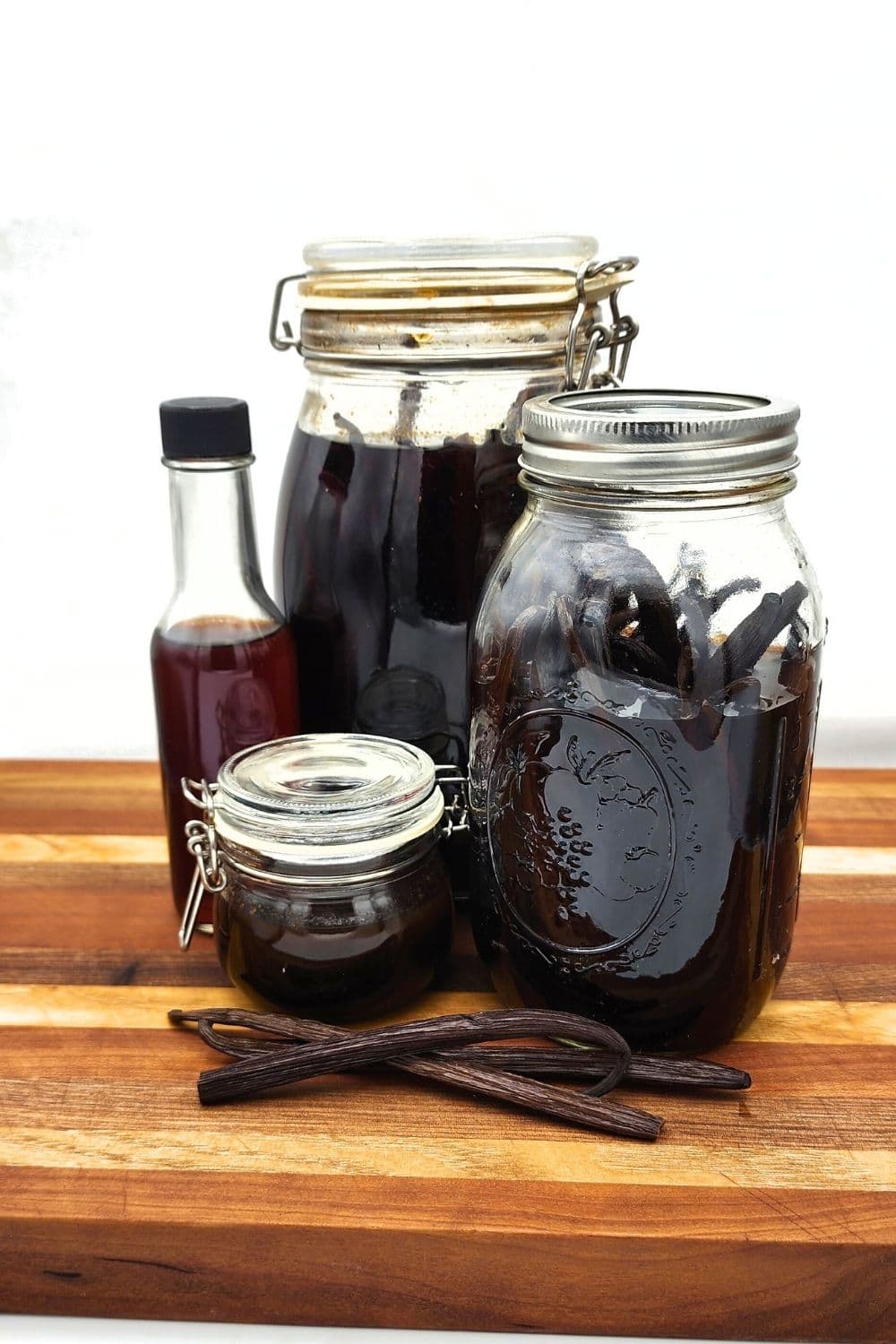 Vanilla beans next to a bottle of extract and a bowl of vanilla paste