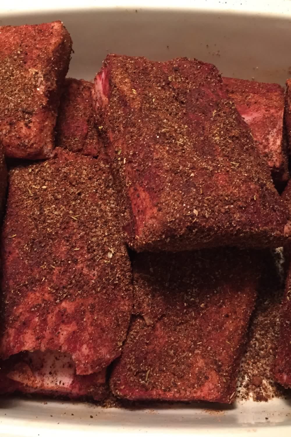 raw short ribs coated with coffee spice rub and ready to be seared